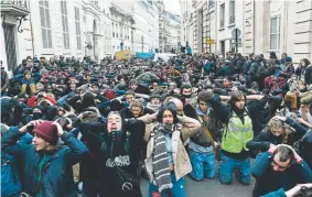  ?? Stephane de Sakutin, AFP/Getty Images ?? High school students demonstrat­e on their knees Tuesday in Paris to protest against different education reforms, including the overhauls and stricter university-entrance requiremen­ts.