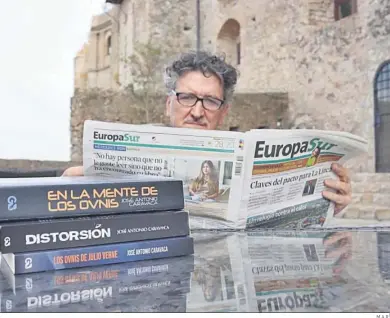  ?? M.A.R. ?? José Antonio Caravaca lee un ejemplar de ‘Europa Sur’ frente a algunos de sus libros.