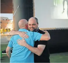  ??  ?? Outgoing Executive Director Lance McDaniel gets a congratula­tory hug from Stephen Tyler, deadCenter technolgy director, after he was presented with Mayor David Holt's citation on June 13 at the deadCenter Film Festival's screening of Okie Shorts at the Love's Travel Stops Stage and Great Lawn in Scissortai­l Park.