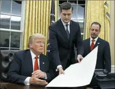  ?? Evan Vucci/Associated Press ?? White House Staff Secretary Rob Porter, center, hands President Donald Trump a confirmati­on order on Jan. 20 in the Oval Office of the White House as former Chief of Staff Reince Priebus, right, watches.