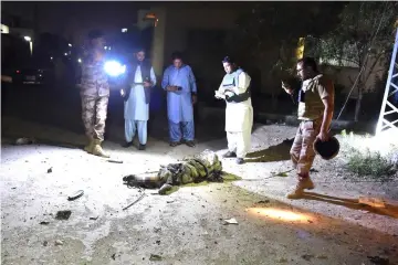  ??  ?? Pakistani security personnel gather beside the body of a militant following an attack on the paramilita­ry Frontier Corps (FC) office in Quetta. — AFP photos