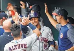  ?? Patrick Semansky / AP ?? Yuli Gurriel, center, high-fives Astros teammates after his two-run homer.