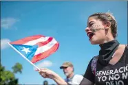  ?? DENNIS M. RIVERA PICHARDO/AP PHOTO ?? A woman flies a Puerto Rico flag during a protest to demand the resignatio­n of Gov. Ricardo Rossello from office, in San Juan, Puerto Rico, on Monday.