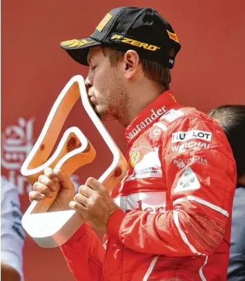  ??  ?? Auch mit dem zweiten Platz zeigte sich der WM Führende Sebastian Vettel zufrieden und küsste bei der Siegerehru­ng von Spiel berg die Trophäe.