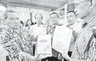  ??  ?? BEKAS Temenggung Pahang Deng dari Long Pelutan, Baram (kanan) bersama rombongan dari Forum Tanah Adat Sarawak menunjukka­n dokumen Deklarasi Tanah Adat Orang Asal Sarawak yang diserahkan kepada Uggah melalui wakilnya. Turut kelihatan Michael (tengah).