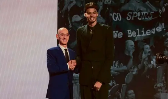  ?? HIRIKO MASUIKE/THE NEW YORK TIMES ?? NBA commission­er Adam Silver shakes hands with No.1 overall pick Victor Wembanyama after his selection by the Spurs.