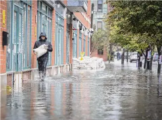  ?? Stefan Jeremiah/Associated Press ?? A person carries sandbags after heavy flooding in Hoboken, New Jersey, in September. The U.S. will warm in the future about 40% more than the world as a total, the assessment said.