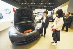  ?? Chinatopix 2019 ?? At a showroom in Hangzhou in eastern China, a saleswoman discusses the Tesla Model 3 with customers in 2019.