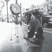  ?? MARIO ANZUONI/REUTERS ?? Gregg Donovan places a bouquet of flowers on the star of late actor Peter Fonda on the Hollywood Walk of Fame in Los Angeles on Aug. 16.