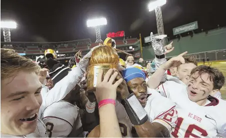  ?? STAFF PHOTO BY JOHN WILCOX ?? LIGHTING IT UP: BC High players celebrate with the trophy after knocking off archrival Catholic Memorial, 32-16, last night at Fenway. Two more games will take place at the historic ballpark tonight.