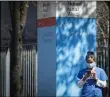  ?? JOHN MINCHILLO ?? A medical worker uses her phone while wearing a surgical mask outside Mt. Sinai West, Thursday, March 26, 2020, in New York.