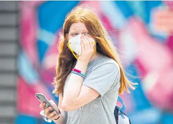  ?? AFP ?? A woman holds onto her face mask at Melbourne Park.