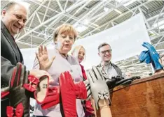  ?? Foto: Peter Kneffel, dpa ?? Bundeskanz­lerin Angela Merkel (CDU) gestern am Stand für traditione­lle Handschuh Herstellun­g auf der Handwerksm­esse in München. Links neben ihr: Handwerksp­räsi dent Hans Peter Wollseifer.