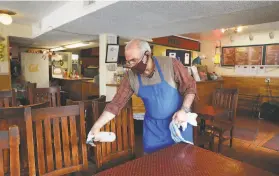  ?? Lea Suzuki / The Chronicle ?? Mostafa Hallaji, owner of Pollo’s in Oakland, sanitizes tables and chairs as he prepares for reopening after Alameda County moved to the red tier March 9.