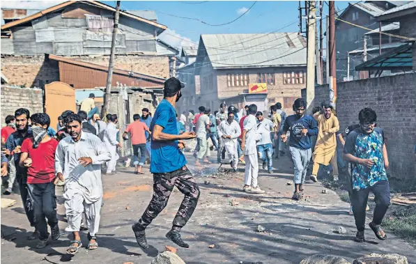  ??  ?? Kashmiri protesters run for cover as Indian police chase them during a protest in Srinagar. The authoritie­s tightened restrictio­ns ahead of the separatist call for a march to the United Nations Military Observers office