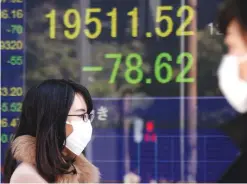  ??  ?? TOKYO: People walk by an electronic stock board of a securities firm in Tokyo yesterday.—AP