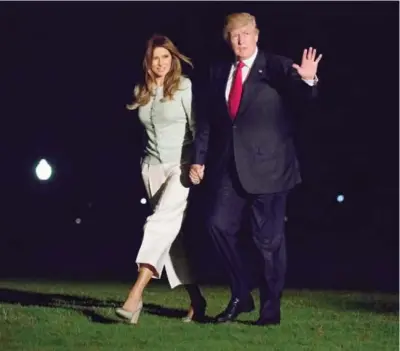  ?? ?? WASHINGTON: US President Donald Trump and first lady Melania Trump walk from Marine One across the South Lawn to White House in Washington on Saturday as they return from Sigonella, Italy. — AP