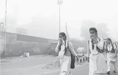  ??  ?? ANCAM KESELAMATA­N: Para pelajar berjalan kaki ke sekolah dalam asbut tebal di New Delhi, semalam.