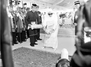  ?? - Bernama photo ?? Tuanku Hajah Haminah pouring scented water at the grave of the late Sultan of Kedah Sultan Abdul Halim.