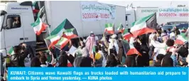  ?? — KUNA photos ?? KUWAIT: Citizens wave Kuwaiti flags as trucks loaded with humanitari­an aid prepare to embark to Syria and Yemen yesterday.