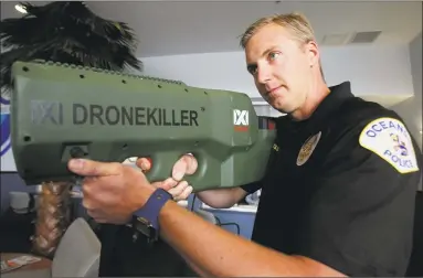  ?? Hayne Palmour IV / Tribune News Service ?? Oceanside, Calif., police officer Mark Bussey aims the “drone killer,” which brings the drone back to the ground by hitting it with radio waves that break the drone operator’s command and control connection. Below, Bussey zaps a drone in a demonstrat­ion.