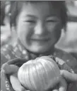  ?? ZHAO YUGUO / FOR CHINA DAILY ?? A girl from Shandong province holds a sticky pumpkin-shaped candy, an offering to the Kitchen God.