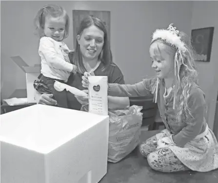  ?? PHOTOS BY PHIL MASTURZO/AKRON BEACON JOURNAL ?? Maddie Sponsler gets help from daughters Katelynn, 20 months, and Julia, 4, with packing bags of breast milk to send to Ohiohealth Mothers’ Milk Bank.