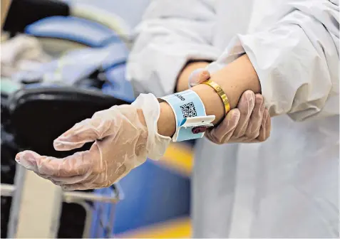  ??  ?? An arrival at Hong Kong airport in protective gear including a tracking bracelet to monitor the movements of those in varying levels of quarantine and, below, Taipei’s strict travel rules are observed on the Metro in Taiwan, pictured on March 7