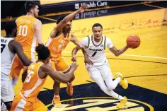  ?? Associated Press ?? ■ Missouri’s Xavier Pinson, right, passes the ball past Tennessee’s Keon Johnson, center, during the second half of an NCAA basketball game Wednesday in Columbia, Mo.