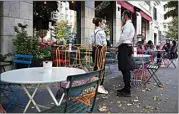  ?? ANDREW MEDICHINI / AP ?? A waiter and a waitress wearing masks wait for customers Tuesday in Rome.