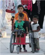  ?? AAREF WATAD / AFP / GETTY IMAGES ?? Displaced Syrian children push a boy on a makeshift wheelchair at a displaced people camp in Idlib province, which is being targeted by Syrian forces, at top.