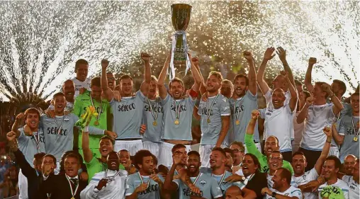  ?? — AFP ?? Champions: Lazio players and coaching staff celebrate with the trophy after beating Juventus in the Italian Super Cup final at the Olympic Stadium on Sunday.