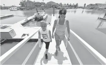  ?? DOUG DURAN/STAFF PHOTOS ?? Lorrie Champ, of Discovery Bay, and her grandson Jaden, 9, walk up her backyard dock ramp Wednesday in Discovery Bay, where a bloom of blue-green algae has led health officials to warn people to avoid the water while tests are conducted.