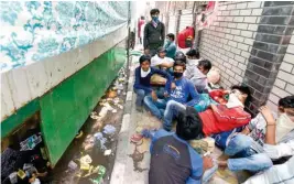  ?? PTI ?? Migrants sit on a pavement outside a government school at Vinod Nagar on Saturday