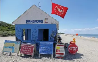  ?? STuART CAHILL / HeRALd sTAff fILe ?? BEWARE: Signs at Plymouth Long Beach warn of sharks as the no-swimming flag flies after a shark was sighted nearby. At top, a great white shark tries to bite a fish head being trolled through the water off South Africa.