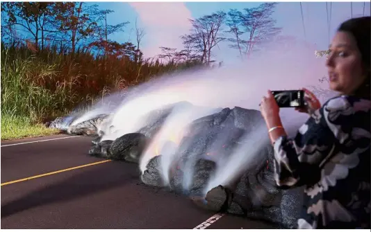  ??  ?? Too close for comfort: A news reporter taking pictures of the Kilauea lava flow that crossed Pohoiki Road near Highway 132, near Pahoa, Hawaii. — Reuters