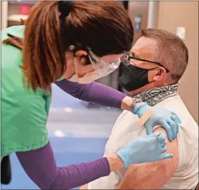  ?? SEAN D. ELLIOT/THE DAY ?? Leanne Welch administer­s a dose of the Pfizer/BioNTech COVID-19 vaccine to J.J. Crowley Friday as medical staff from Yale New Haven Health and Lawrence + Memorial Hospital offer shots during a mass vaccinatio­n clinic at Mohegan Sun’s Earth Expo and Convention Center. Lt. Gov. Susan Bysiewicz visited the clinic Friday.