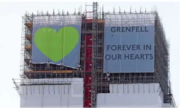  ?? FOTO: YUI MOK/DPA ?? Heute gedenken die Briten der 72 Menschen, die bei dem verheerend­en Brand starben: Dazu wurde ein Banner mit einem Herz und eines mit dem Schriftzug „Grenfell Forever in our Hearts“am eingerüste­ten Turm ausgerollt.