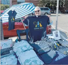  ?? DAVE JOHNSON THE WELLAND TRIBUNE ?? Port Colborne Historical and Marine Museum assistant curator Michelle Mason shows a Canal Days T-shirt at the Farmers' Market.