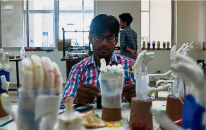  ??  ?? Making a difference: A technician working on prosthetic hands at the Bhagwan Mahaveer Viklang Sahayata Samiti non-profit organisati­on’s main branch in Jaipur. (Left) A man helping his wife to walk for the first time with her first rubber-based...