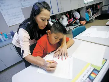  ?? LUIS SÁNCHEZ SATURNO/THE NEW MEXICAN ?? Fourth-grade teacher Alysia Boylan works with Christophe­r Garcia, 10, during a cursive lesson Tuesday at Piñon Elementary School. With more than 60 percent of its students receiving lunch aid and about 16 percent learning English, Piñon received an A...