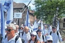  ?? OMAR MARQUES/ GETTY IMAGES ?? Marchers carry Israeli flags as they walk past the gate to the former Nazi concentrat­ion death camp Auschwitz on May 6 in Oswiecim, Poland.