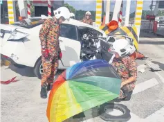  ??  ?? Fire and Rescue personnel with the victim at the crash site. — Bernama photo