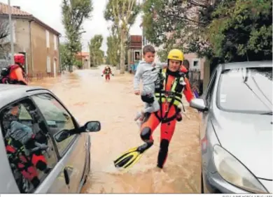  ?? GUILLAUME HORCAJUELO / EFE ?? Un bombero lleva a un niño durante las labores de rescate tras las inundacion­es en la localidad francesa de Trebes.