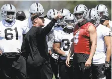  ?? Jeff Chiu / Associated Press ?? Raiders head coach Jon Gruden discusses practice drills with quarterbac­k Derek Carr (4) and other offensive players.