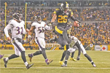  ?? THE ASSOCIATED PRESS ?? Pittsburgh Steelers running back Le’Veon Bell (26) leaps into the end zone ahead of Baltimore Ravens strong safety Eric Weddle (32) for a touchdown during the second half Sunday. Bell ran for 122 yards and scored twice.