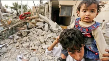  ?? REUTERS ?? A boy carries his sister near the collapsed house of Yemen’s late Prime Minister Faraj Bin Ghanim after it was hit by a Saudi-led air strike in Sanaa on Thursday.