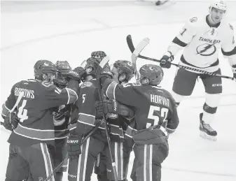  ??  ?? Alex Burrows, left, and fellow Canucks players congratula­te Luca Sbisa, centre, on his goal against Tampa Bay in Vancouver on Friday. Burrows drew the primary assist on the goal.