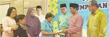  ??  ?? Nasir (second right) presenting a Hari Raya contributi­on to one of the recipients together with Pengiran Saifudin (third right).