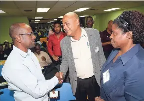  ?? LIONEL ROOKWOOD/PHOTOGRAPH­ER ?? Newly elected president of the JFF Micheal Ricketts is congratula­ted by Horace Reid. Looking on is JFF Director